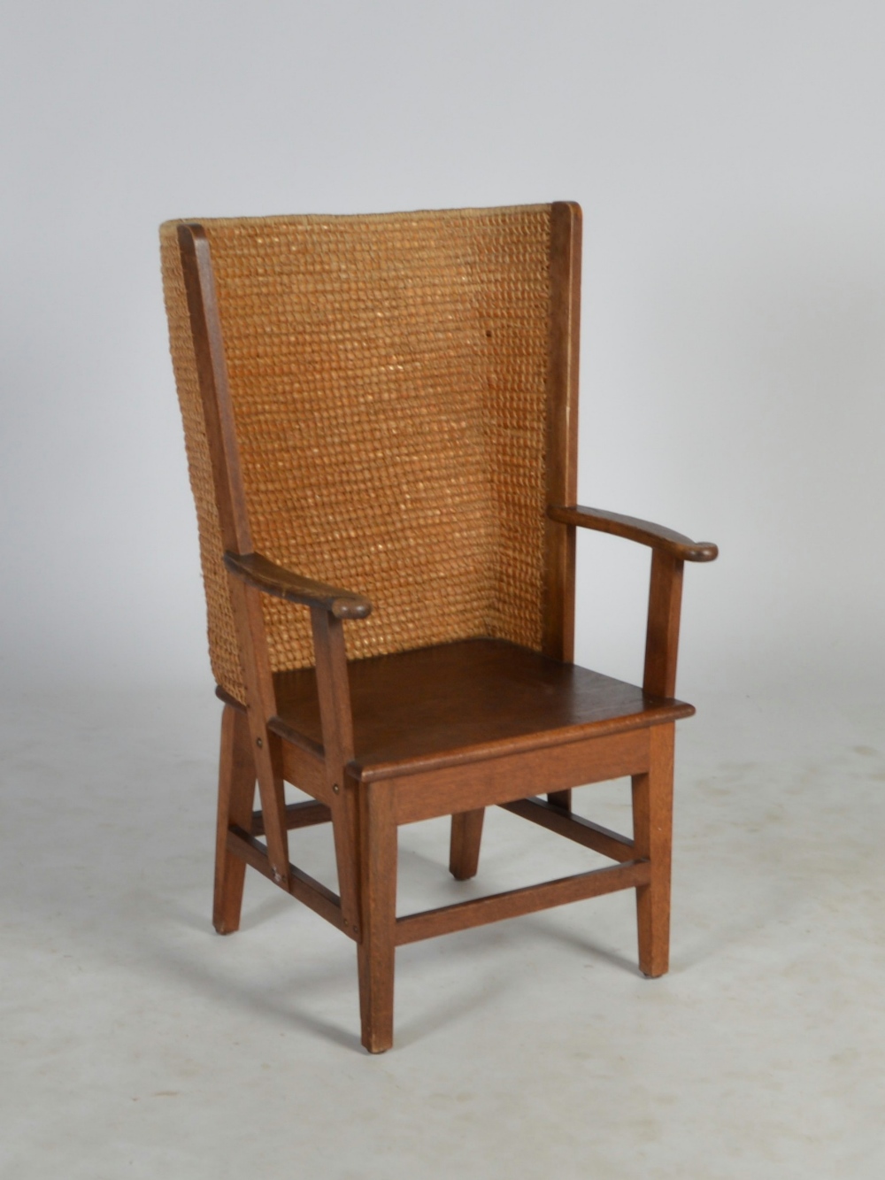 An early 20th century oak Orkney chair, the woven back above a solid panel seat, flanked by arms