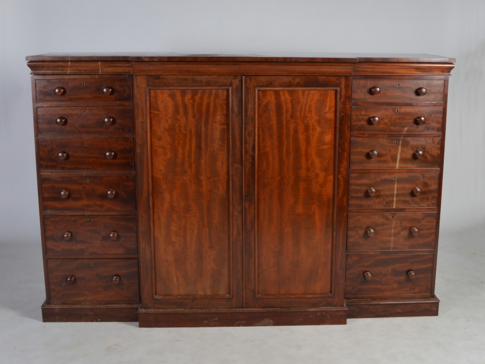 A 19th century mahogany breakfront chest/ cupboard, the moulded cornice above a pair of panelled