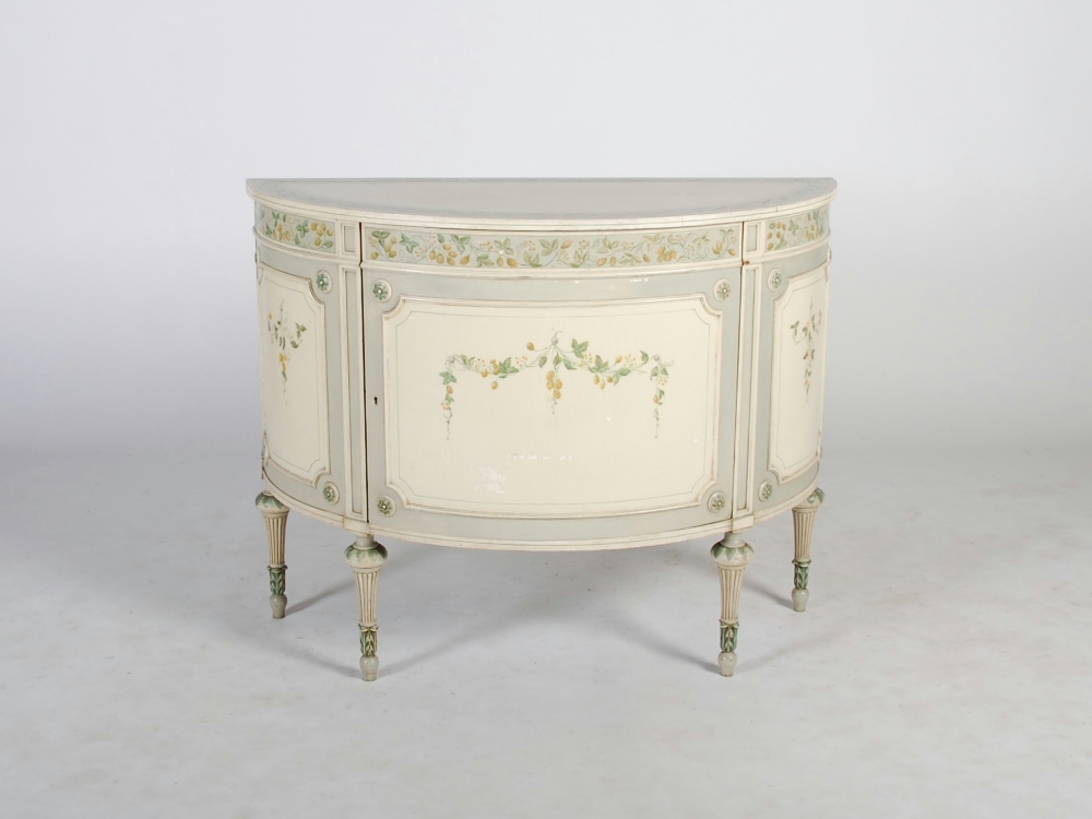 A Neo-Classical style cream and green painted demi-lune cabinet, the shaped top above a frieze