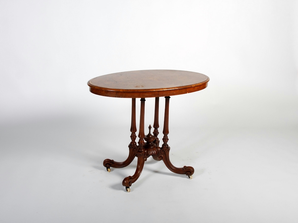 A Victorian walnut, ebony and boxwood lined centre table, the oval top centred with a scroll work