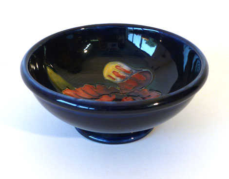 A Moorcroft miniature bowl decorated in the "Iris" pattern on a cobalt blue ground, with paper