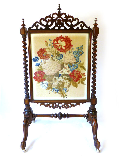 A Victorian rosewood fire screen, the tapestry floral insert under glass in a pierced scrolling