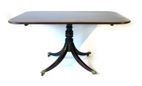 A George III mahogany and cross banded supper table with rectangular tilting top on a quadruple claw