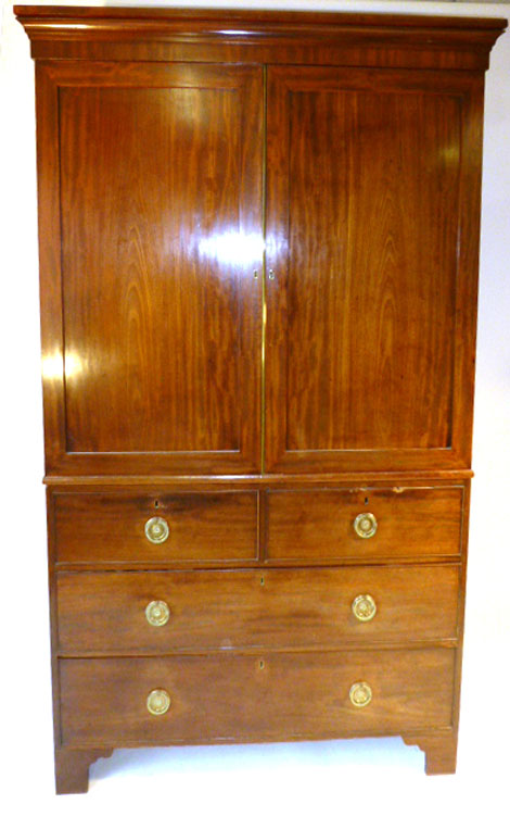 A late Georgian mahogany linen press having two short dummy drawers over two long drawers with brass