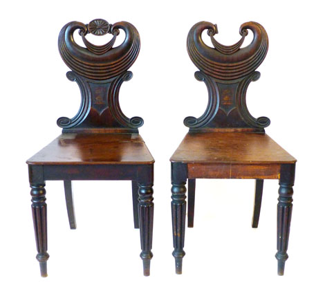 A pair of William IV mahogany hall chairs, the moulded backs painted with armorial devices on turned