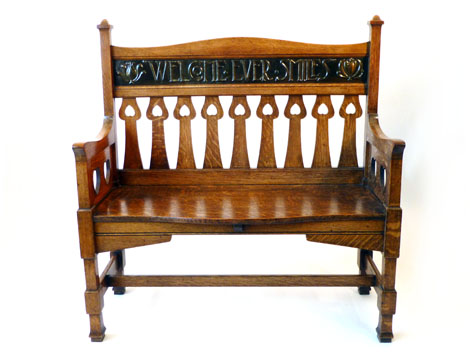 An Arts & Crafts oak two seater settle having heart and tulip decoration with inset embossed