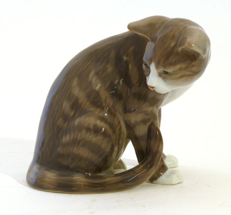 A Royal Copenhagen model of a tabby cat in grey and brown seated looking to its right, No. 301, h.