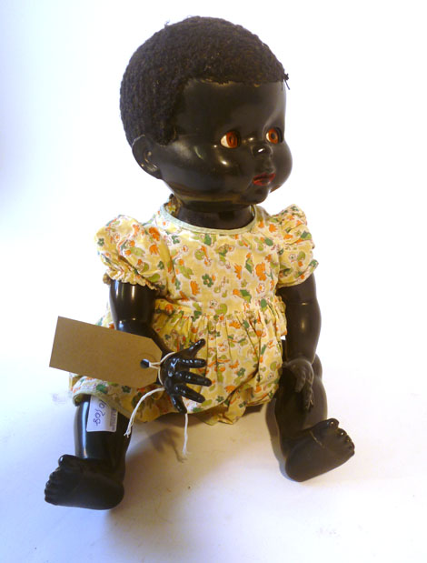 A pedigree black doll together with assorted clothing, dresses, cardigan etc