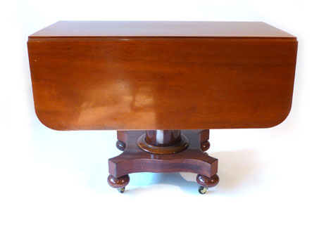 An 19th century American mahogany extending dining table comprising a pair of drop leaf supper