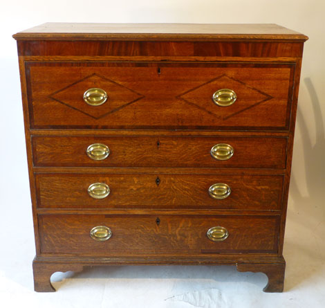 A George III oak and mahogany secretaire chest of four long drawers, the top drawer revealing a