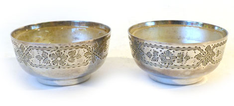 An Edwardian pair of silver salts of squat cylindrical form with bright cut floral borders raised on