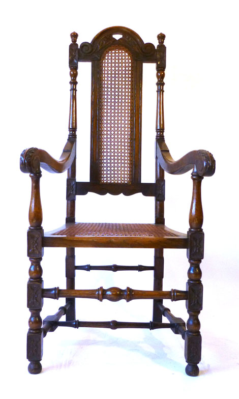 A Carolean style carved chair with arched back and seat, scroll arms on block and turned legs united