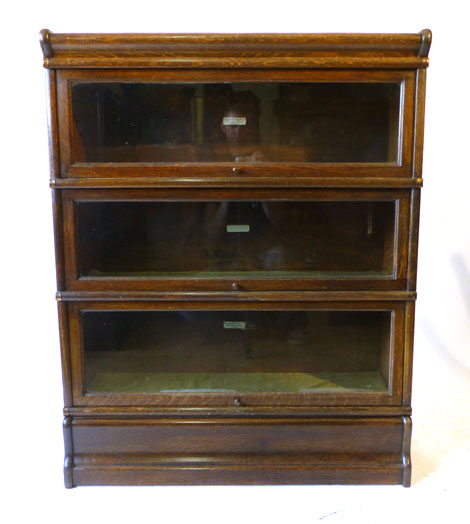 A Globe Wernicke oak three tier book case with glazed shelves on a plinth base with drawer,