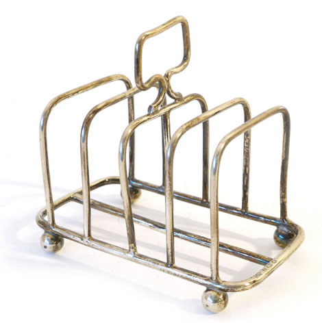 An Edwardian silver four slice toast rack of square form with matching handle raised on four ball