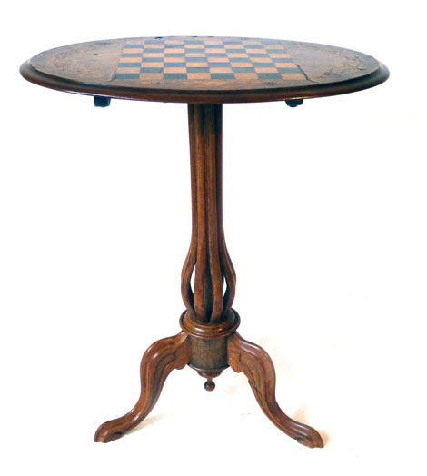 A Victorian walnut oval tilt topped games table with inlaid chest board and foliate border on a