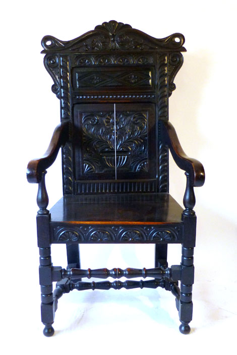 A 17th Century style carved oak Wainscot chair with a carved and panelled back with floral geometric