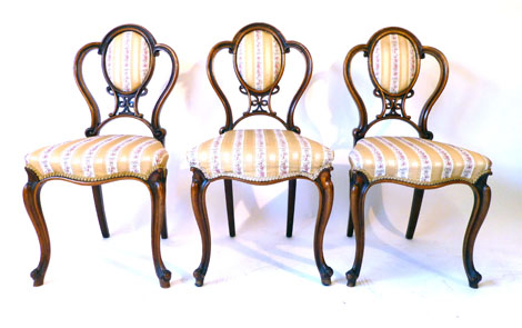 A set of six Victorian balloon back chairs with carved slats and upholstered oval back rest and