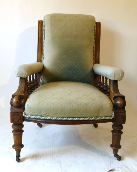 A Victorian walnut fireside chair upholstered in green woven fabric with bowed sear on turned legs