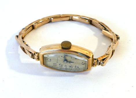 A lady's 9ct gold cased wristwatch in tonneau shape having black Arabic numerals on a silvered