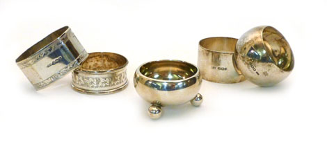 Four assorted silver napkin rings and a silver squat salt on three ball feet, various dates and
