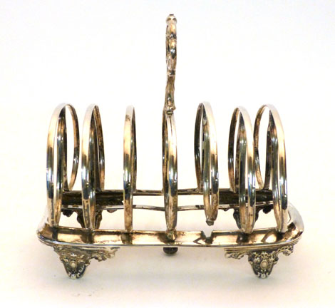 A Victorian silver six slice toast rack with scroll loop handle raised on four scroll feet,