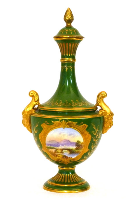 A Coalport twin handled covered vase, painted with a cartouche of a bridge over a river within