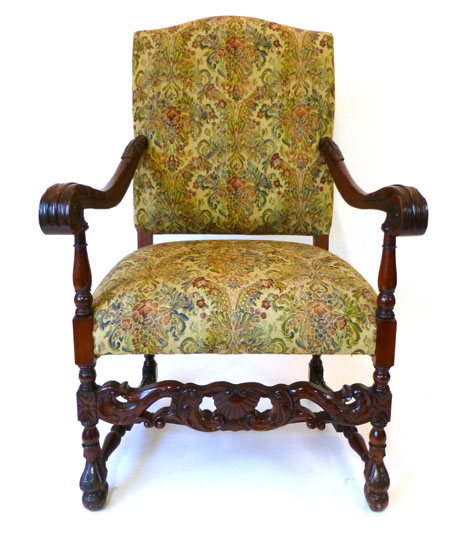 An early 17th century style mahogany chair upholstered in a woven fabric with carved scroll arms and