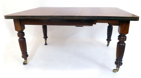 An Edwardian mahogany extending dining table of rectangular form with one extra leaf on turned