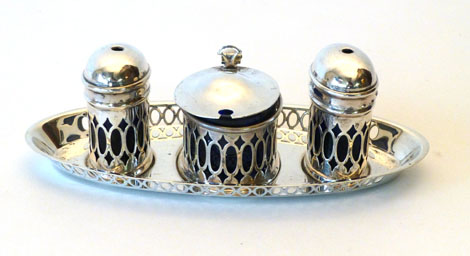 A George V silver three piece cruet set of oval form with pierced Neo-classical style decoration