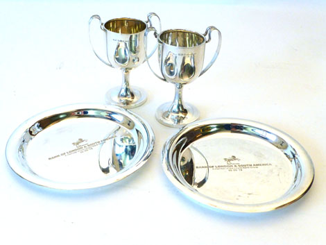 A pair of George V silver twin handled trophy cups with scroll handles raised on a circular pedestal