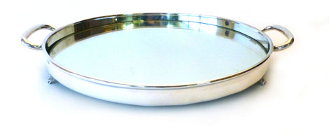 A George VI silver twin handled tray of circular form with a mirrored base raised on three scroll
