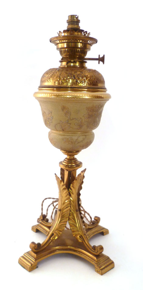 A Victorian gilt metal oil lamp with a pottery chineware decorated well and cast border on a