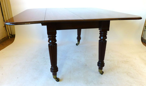 A late Regency mahogany extending Pembroke form dining table with drop leaf D end and three extra