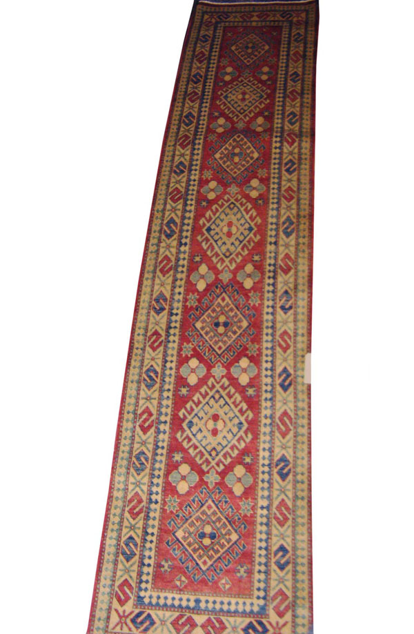 FINE KAZAK RUNNER, repeat diamond medallions on terracotta field, 382cm x 82cm, with scattered