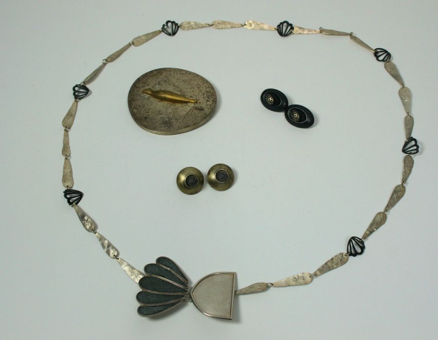 A white metal and leather necklace composed of textured and pierced stylised links, the centre front