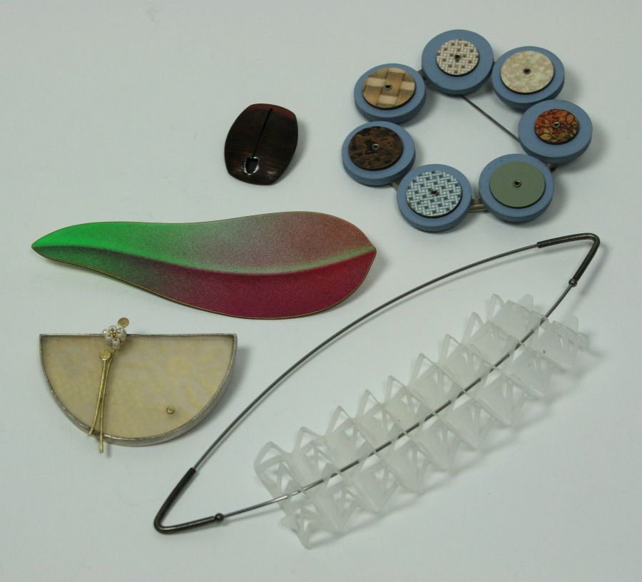 A collection of brooches to include a yellow and white metal brooch by Emma Gail, with lace detail