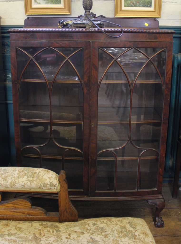 A Georgian style mahogany bow fronted display cabinet with carved top, astragal doors with shelved
