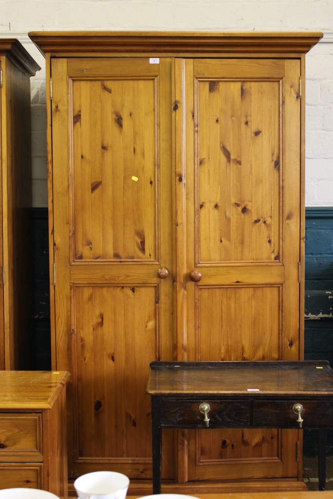 A pine two door wardrobe with corners, shelved and fitted interior, raised on a shaped base