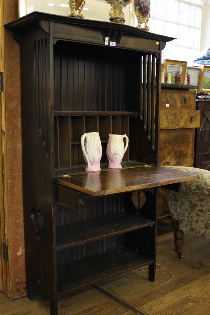An Arts and Crafts oak bureau with shaped cornice, lift down lid with fitted interior, shelf