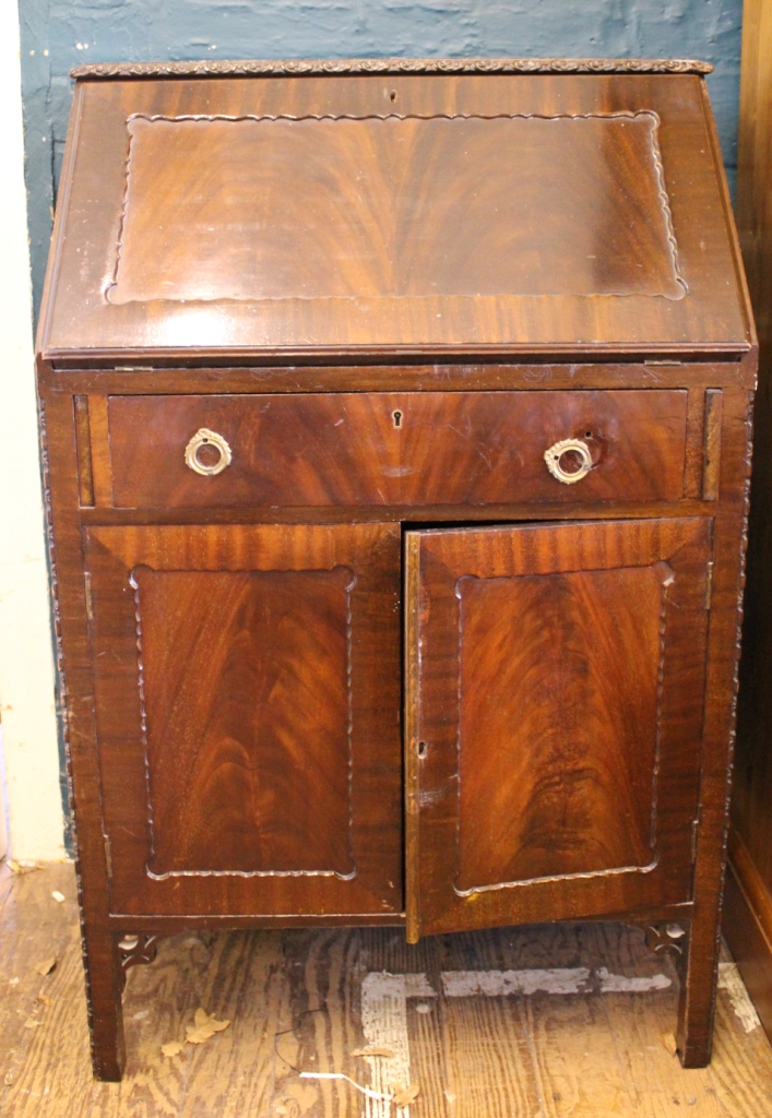 A mid 20th century mahogany bureau with carved edged top, fold down lid with fitted interior over