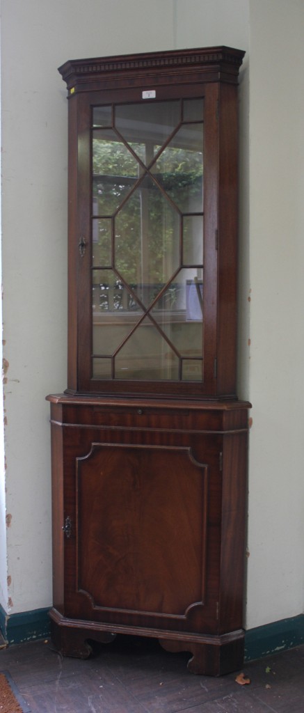 A Georgian style mahogany corner unit with dentil frieze, astragal door with shelved interior