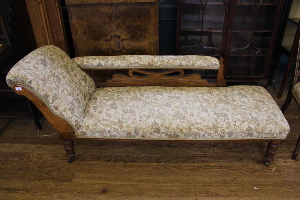 A Victorian oak framed chaise lounge with profuse fret work, floral patterned fabric upholstery,