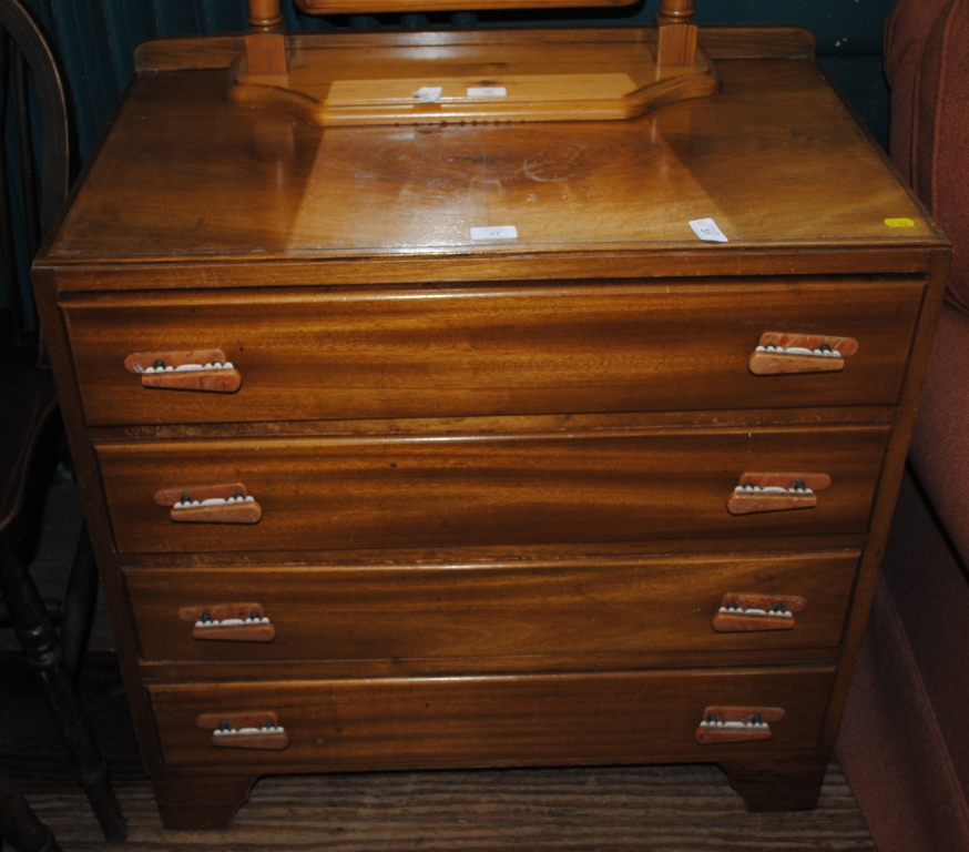 A mid 20th century mahogany chest of four drawers with irregular shaped handles on bracket feet