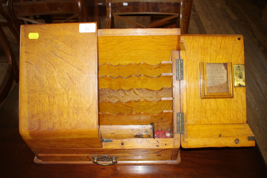 An early 20th century oak desk top stationary holder with fold out doors, fitted interior, one