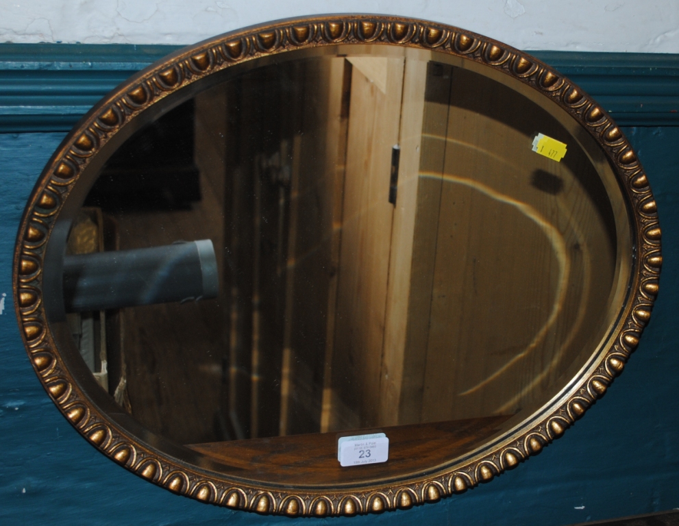 An oval shaped wall mirror with bevelled glass and ornate gilt frame