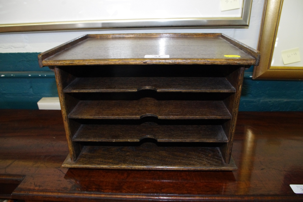 An early 20th century oblong shaped oak desktop stationary holder with shaped top, four shelves