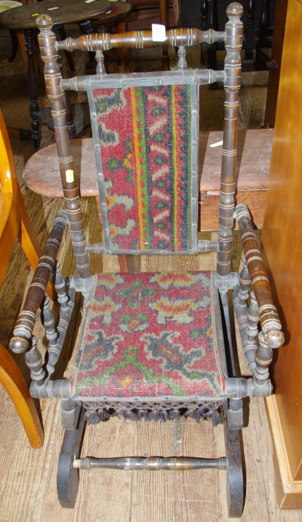 A 19th century mahogany child`s rocking chair with turned supports and arms, upholstered seat on a