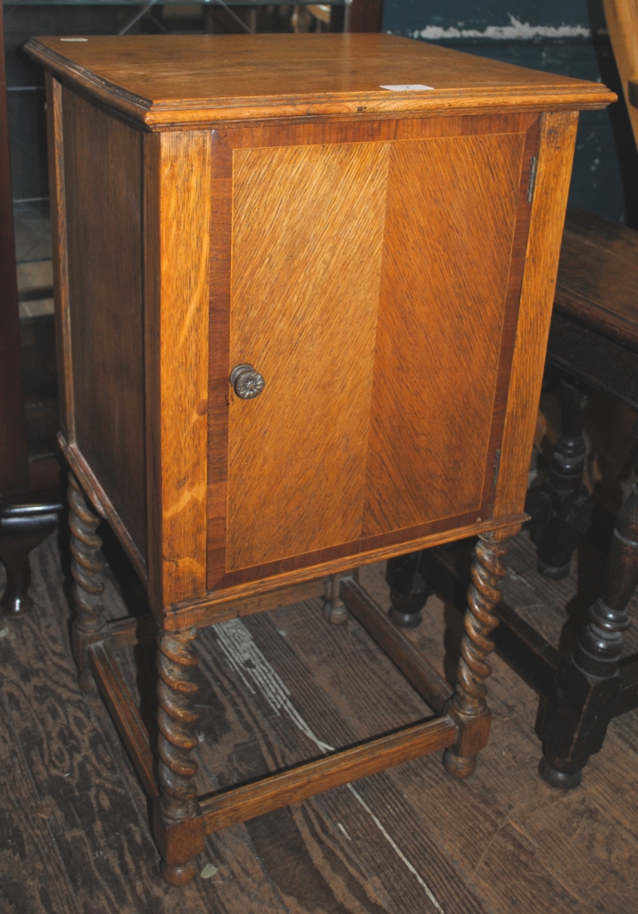 A 19th century oak bedside locker or pot holder with shaped top, cupboard under with brass handle