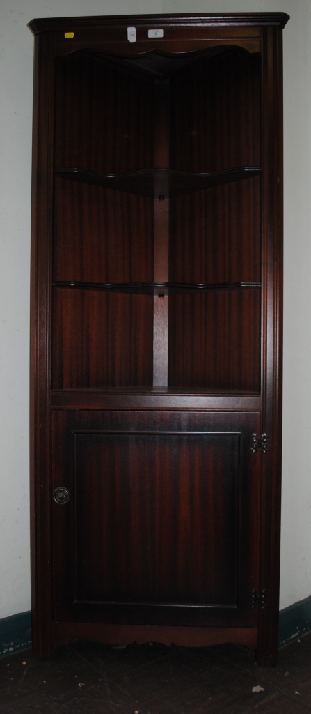 An Edwardian style mahogany corner unit with shelved interior, fluted supports and cupboard under