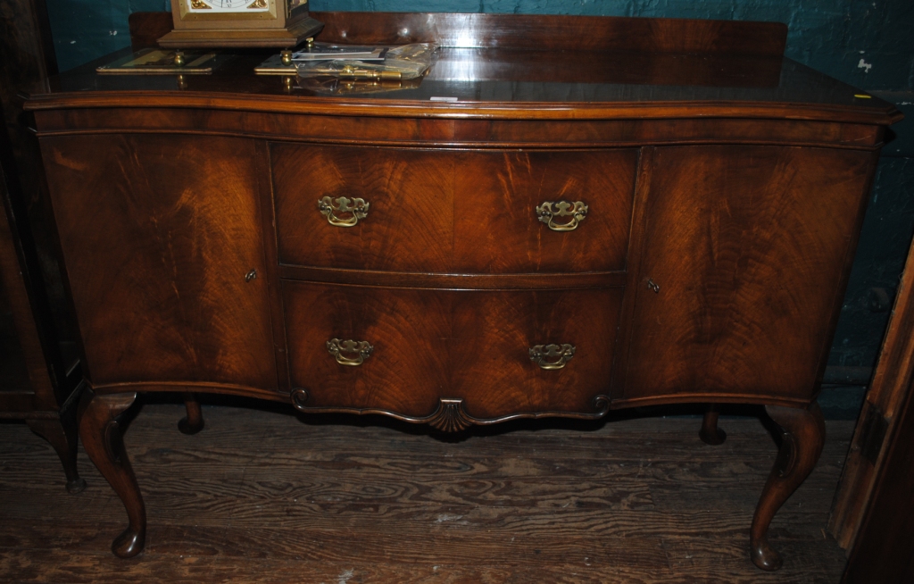 A 19th century mahogany side board with shaped top, serpentine shaped front over two central drawers